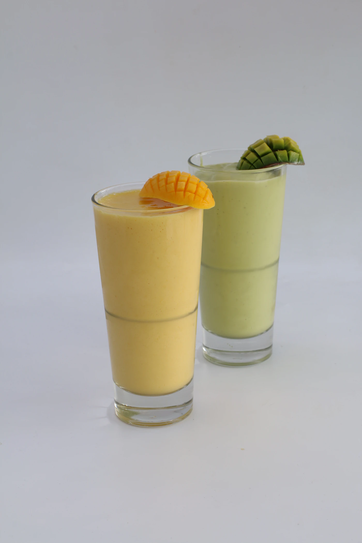 Two glasses of chilled lassi garnished with pistachio