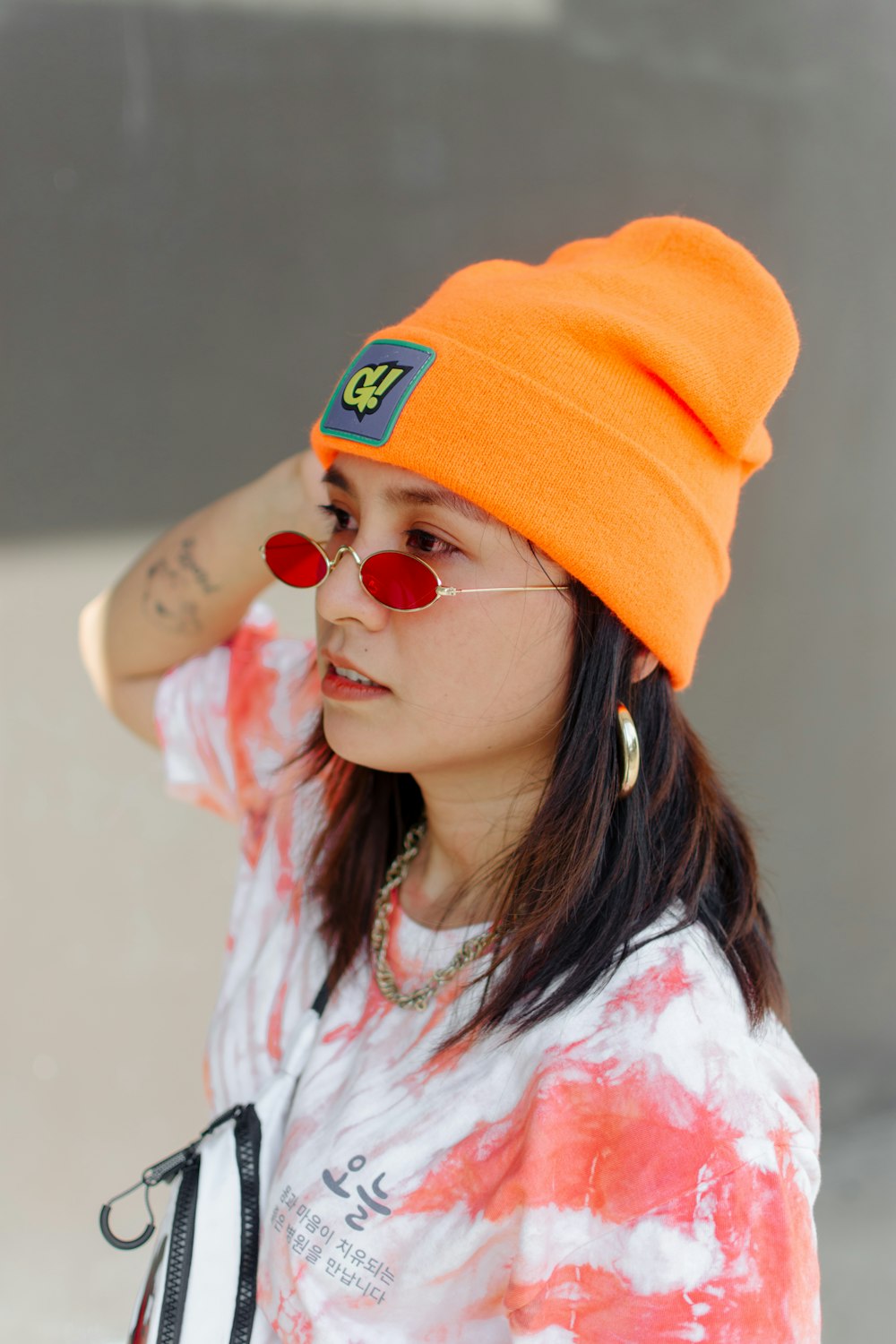 girl in white and pink floral shirt wearing orange knit cap