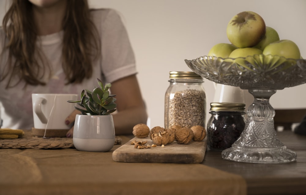 green apple fruit beside clear glass jar on brown wooden table