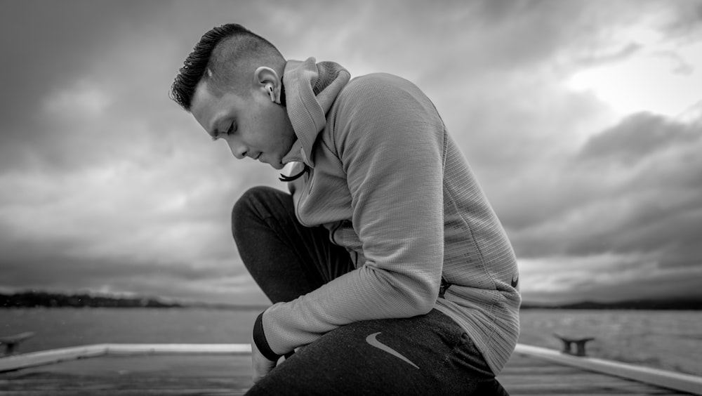 man in long sleeve shirt and black pants sitting on the ground