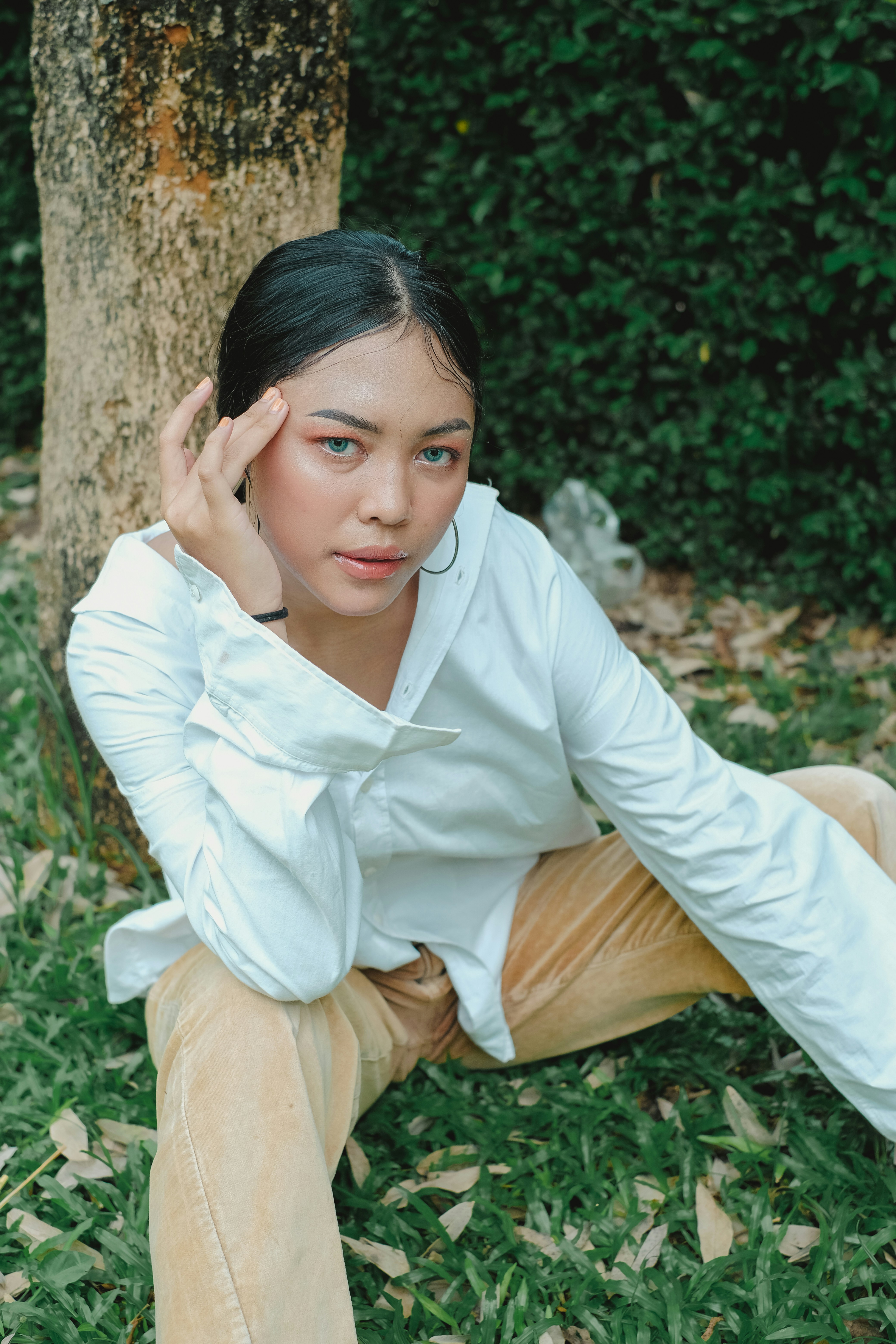 femme en chemise blanche assise sur un tronc d’arbre brun