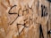 Graffiti in black spray paint spells out 'Scam Demic' on a wooden OSB panel, with parts of other numbers or letters visible nearby.