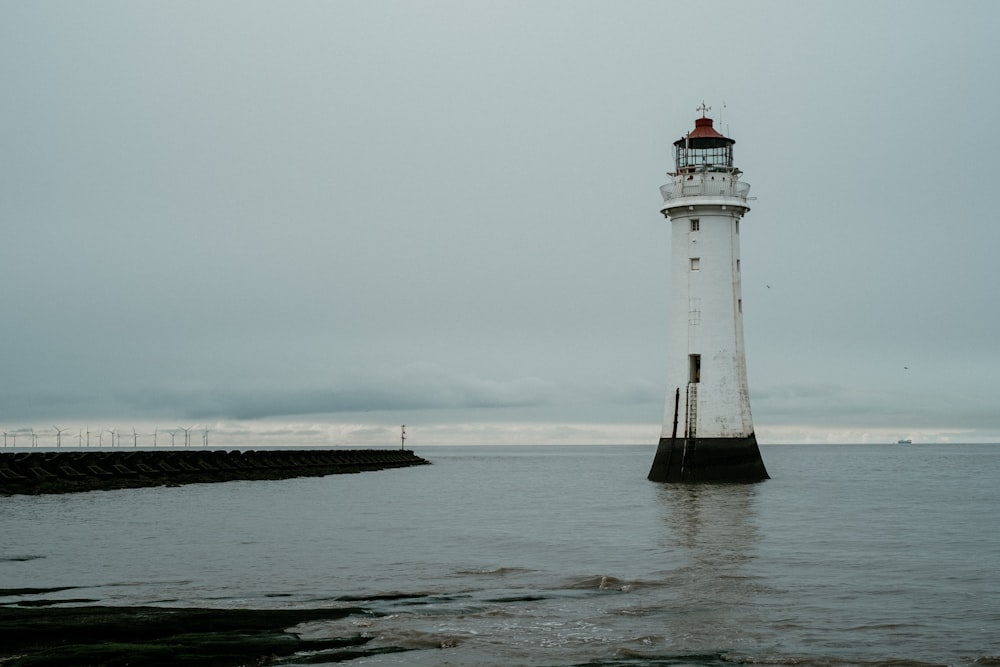 white and black lighthouse on sea dock under white sky during daytime