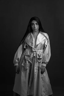 Model wearing a long leather coat with bold red lining, standing confidently in low light