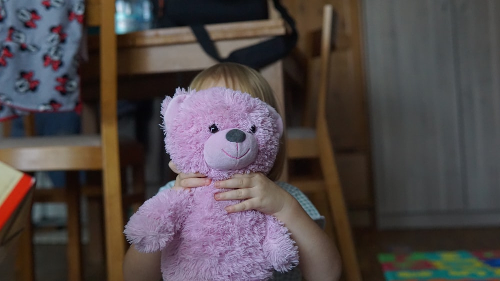 girl holding pink bear plush toy