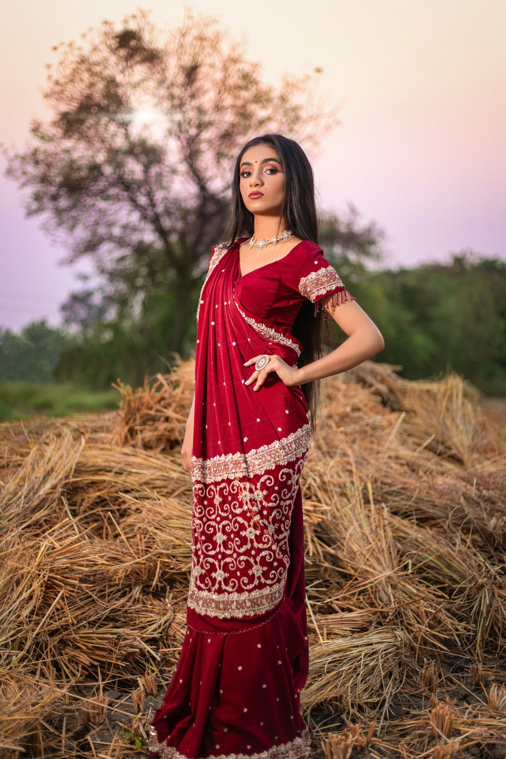 woman in red and white floral dress standing on brown grass field during daytime