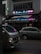 A vibrant bistro pub with a neon sign displaying colorful text in both English and another language. The establishment offers local and western food and advertises live football. Parked in front of the pub are two vehicles, a white van and a silver car, on a dimly lit street.