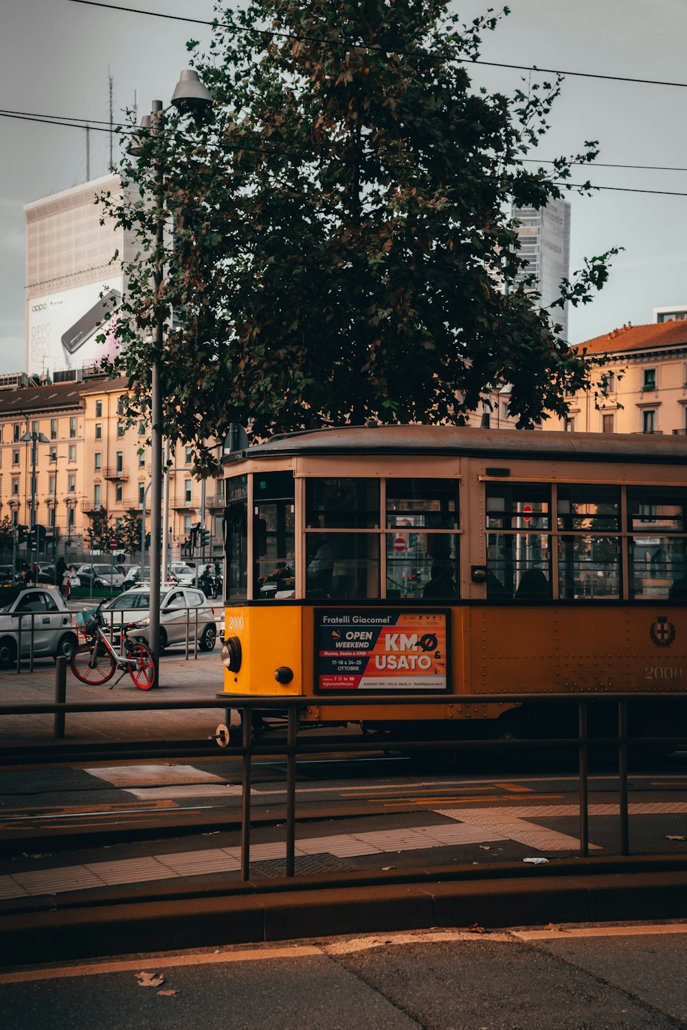 yellow tram on road near green trees during daytime