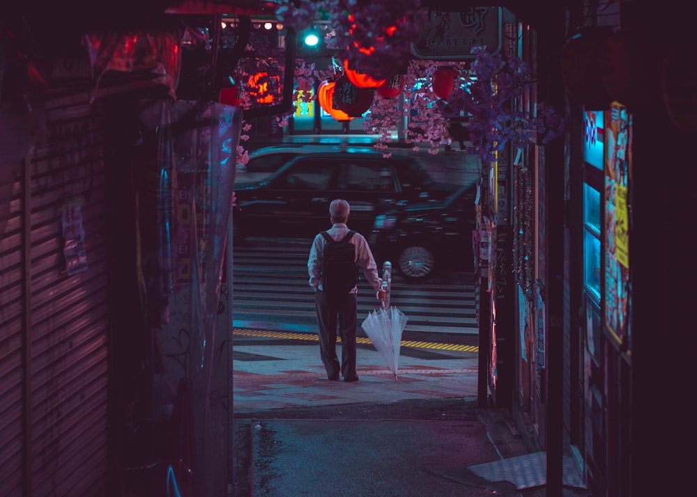 夜間に通りを歩く黒いジャケットの男