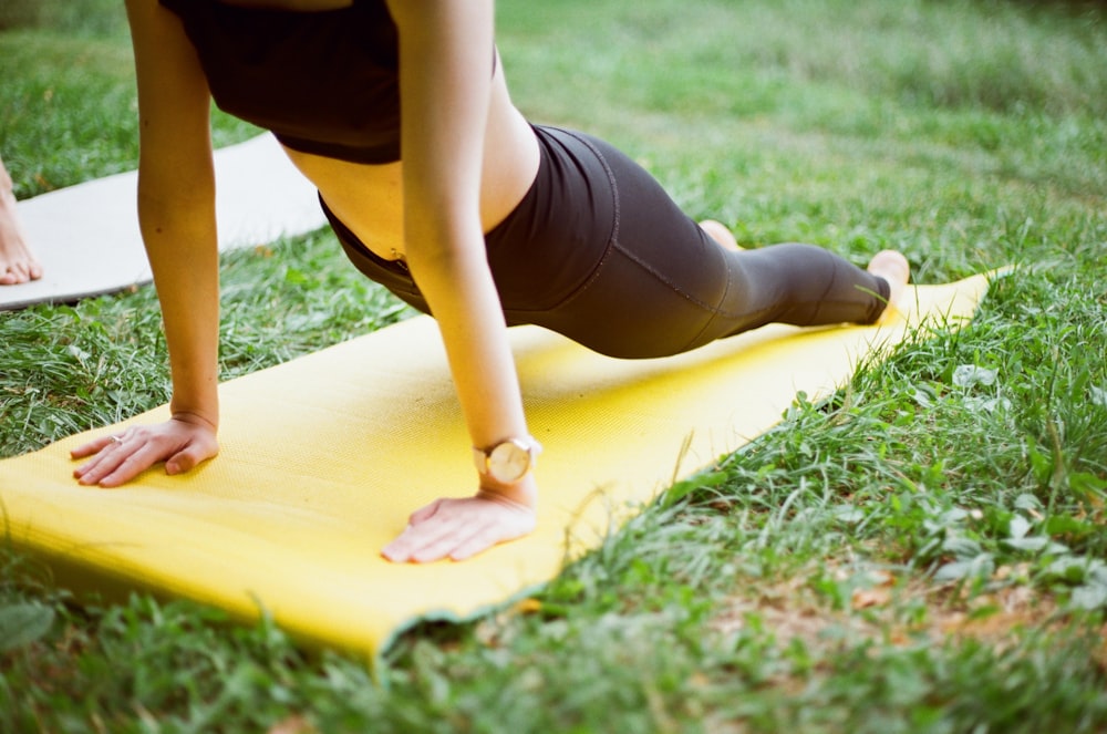 femme en short noir et bas noirs allongée sur une planche de surf jaune