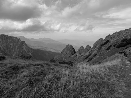A scenic mountain landscape with travelers hiking along a trail.