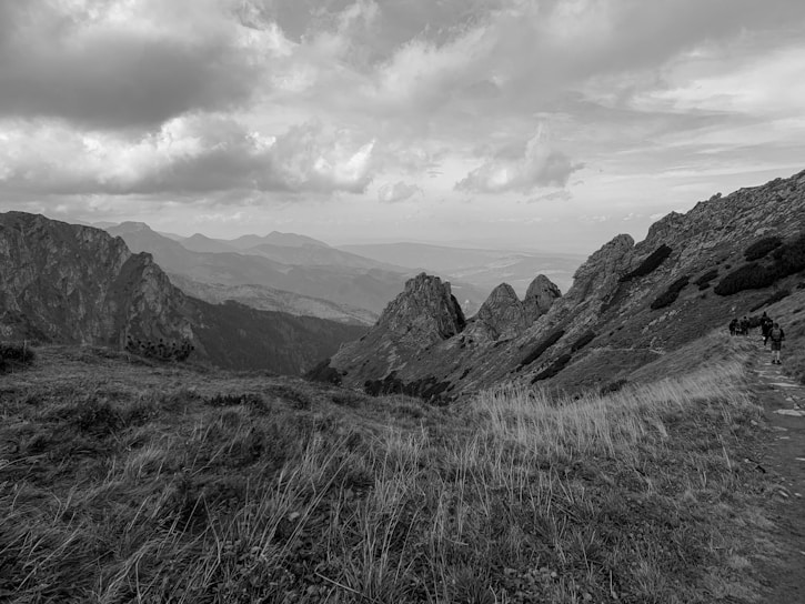 A scenic mountain landscape with travelers hiking on a trail.