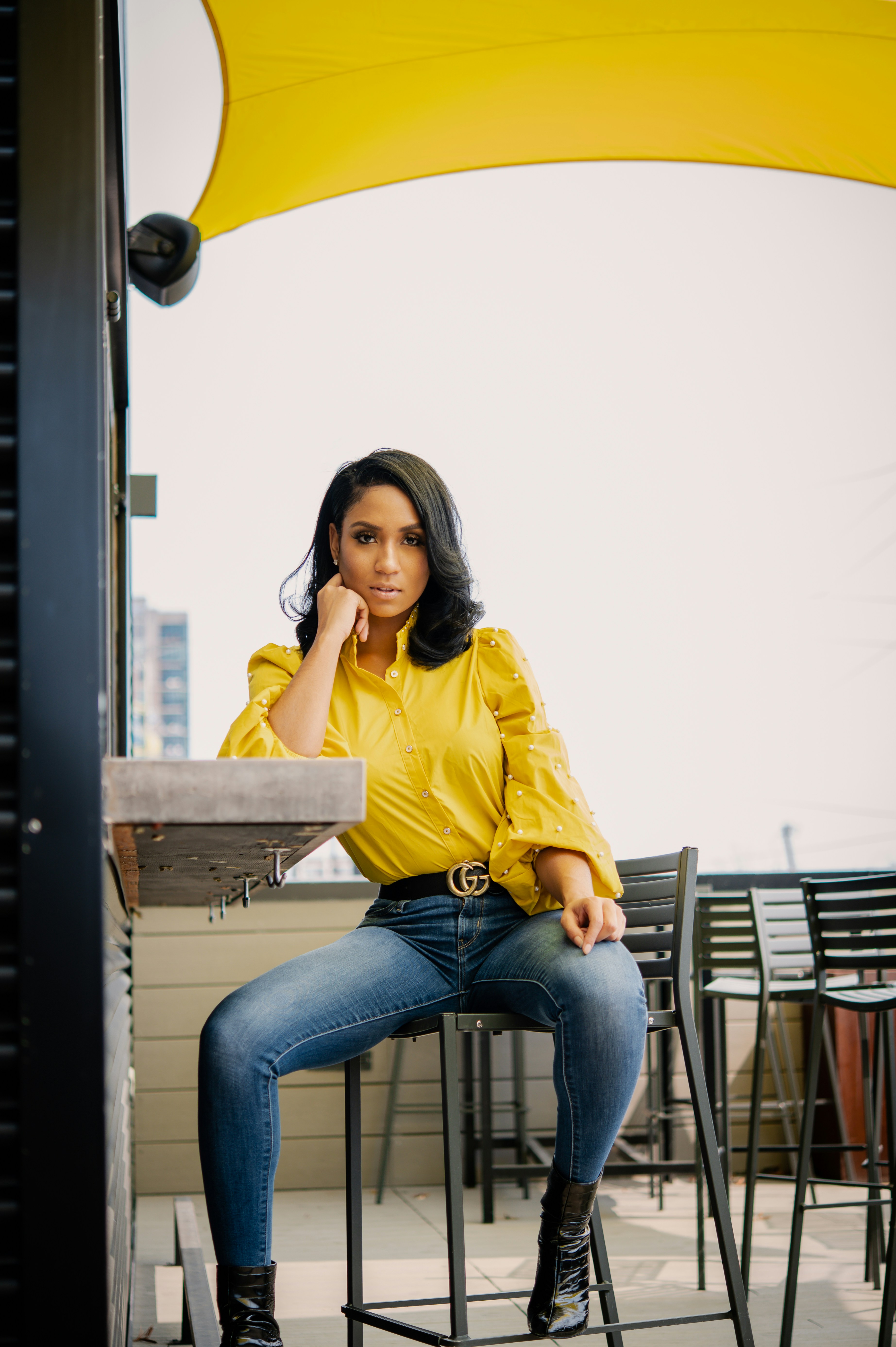 woman-in-yellow-long-sleeve-shirt-and-blue-denim-jeans-sitting-on-brown-wooden-bench