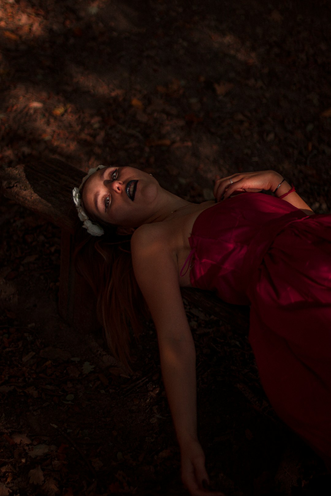 woman in red off shoulder dress lying on ground