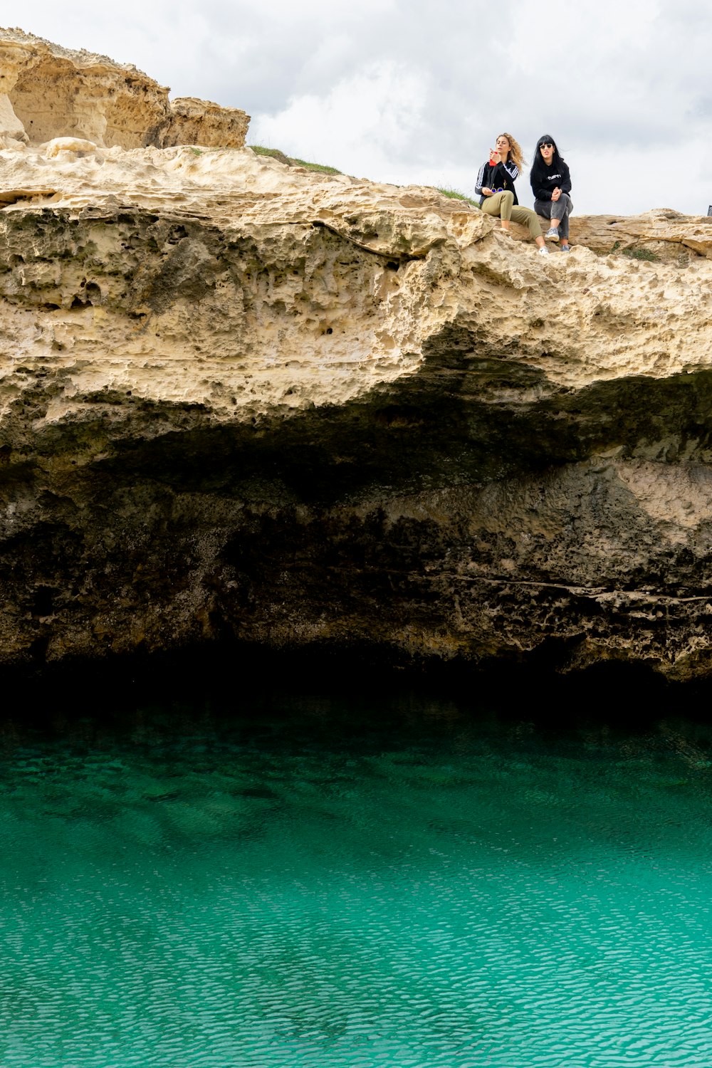 man in blue shorts standing on brown rock near body of water during daytime