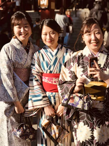 2 women in kimono standing beside woman in black and white dress