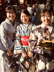 2 women in kimono standing beside woman in black and white dress