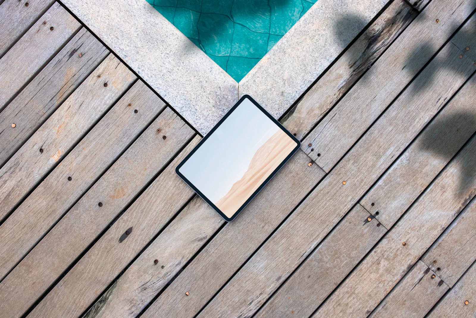 Deck design consultant showing a deck proposal on a tablet to homeowners on their back patio