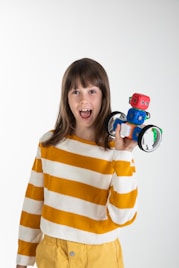 woman in yellow and white striped long sleeve shirt holding red and black toy car