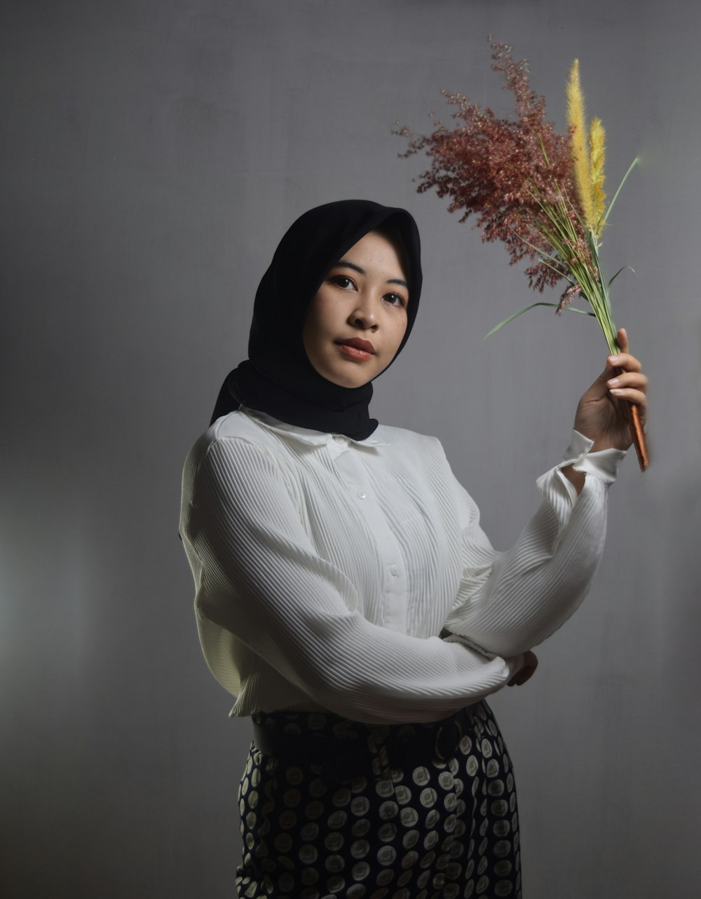 woman in white long sleeve shirt holding green plant