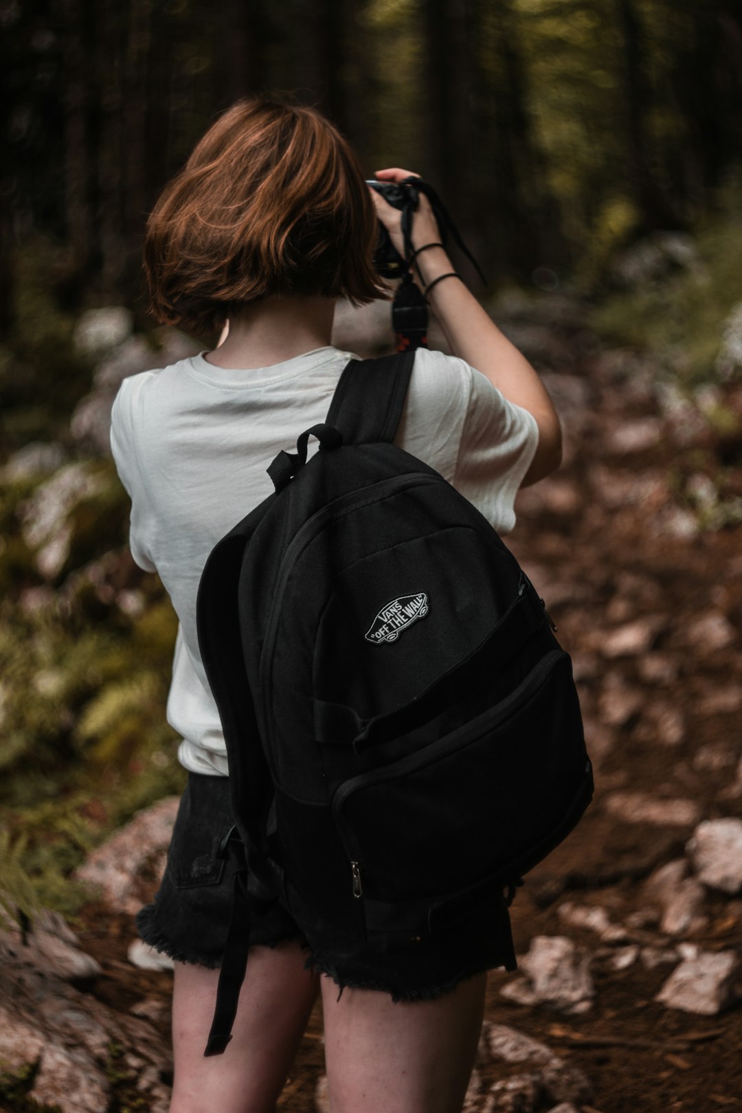 woman in white shirt holding black backpack