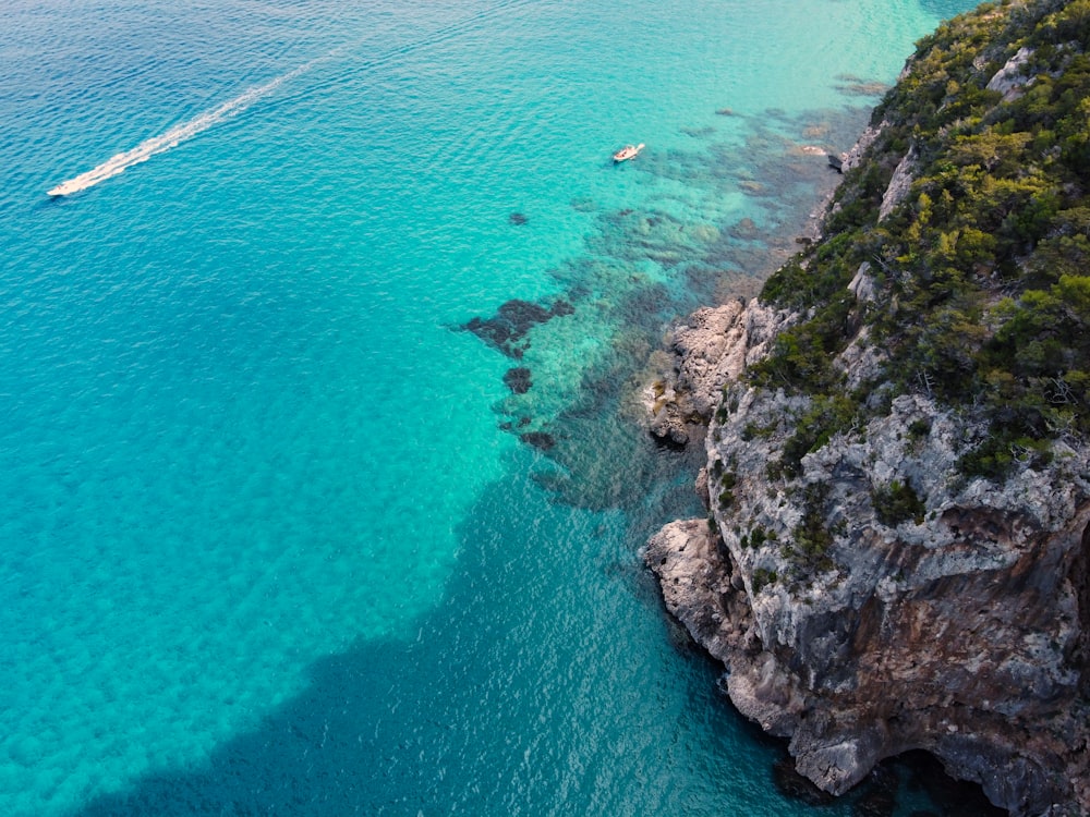 Veduta aerea della formazione rocciosa verde e marrone accanto allo specchio d'acqua durante il giorno