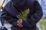 person in black hoodie holding green plant