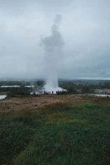 A vibrant photo of the erupting Strokkur geyser with tourists watching nearby.