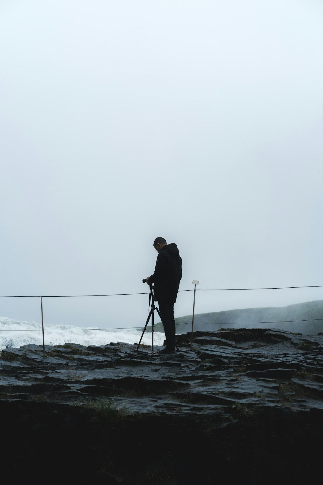 man in black jacket standing on rocky shore during daytime