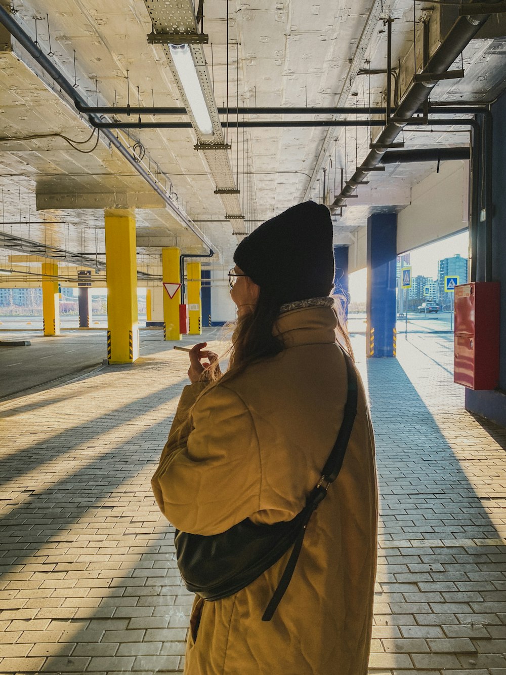 woman in brown coat and black knit cap standing near train station during daytime