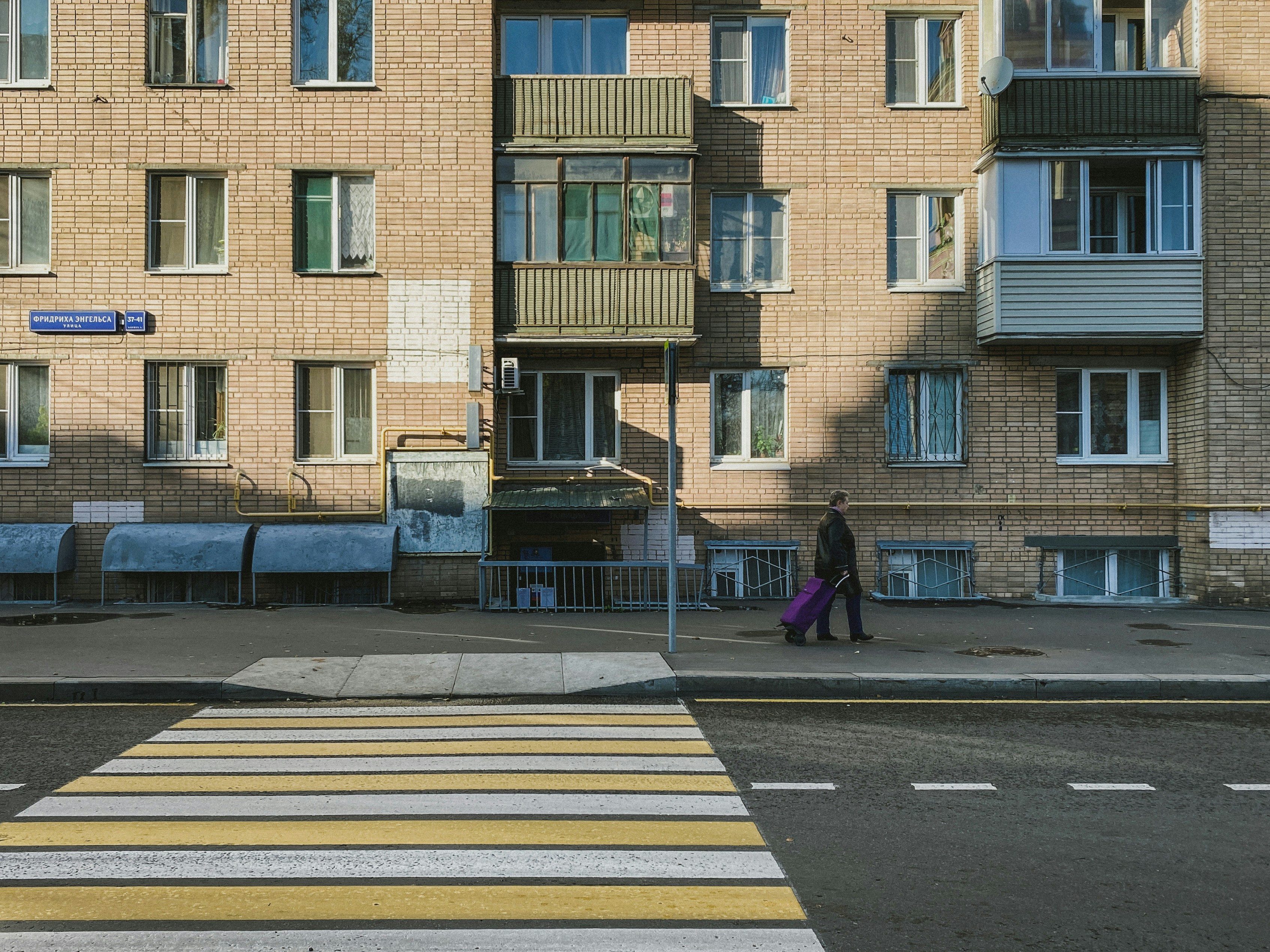 woman in black coat walking on pedestrian lane during daytime