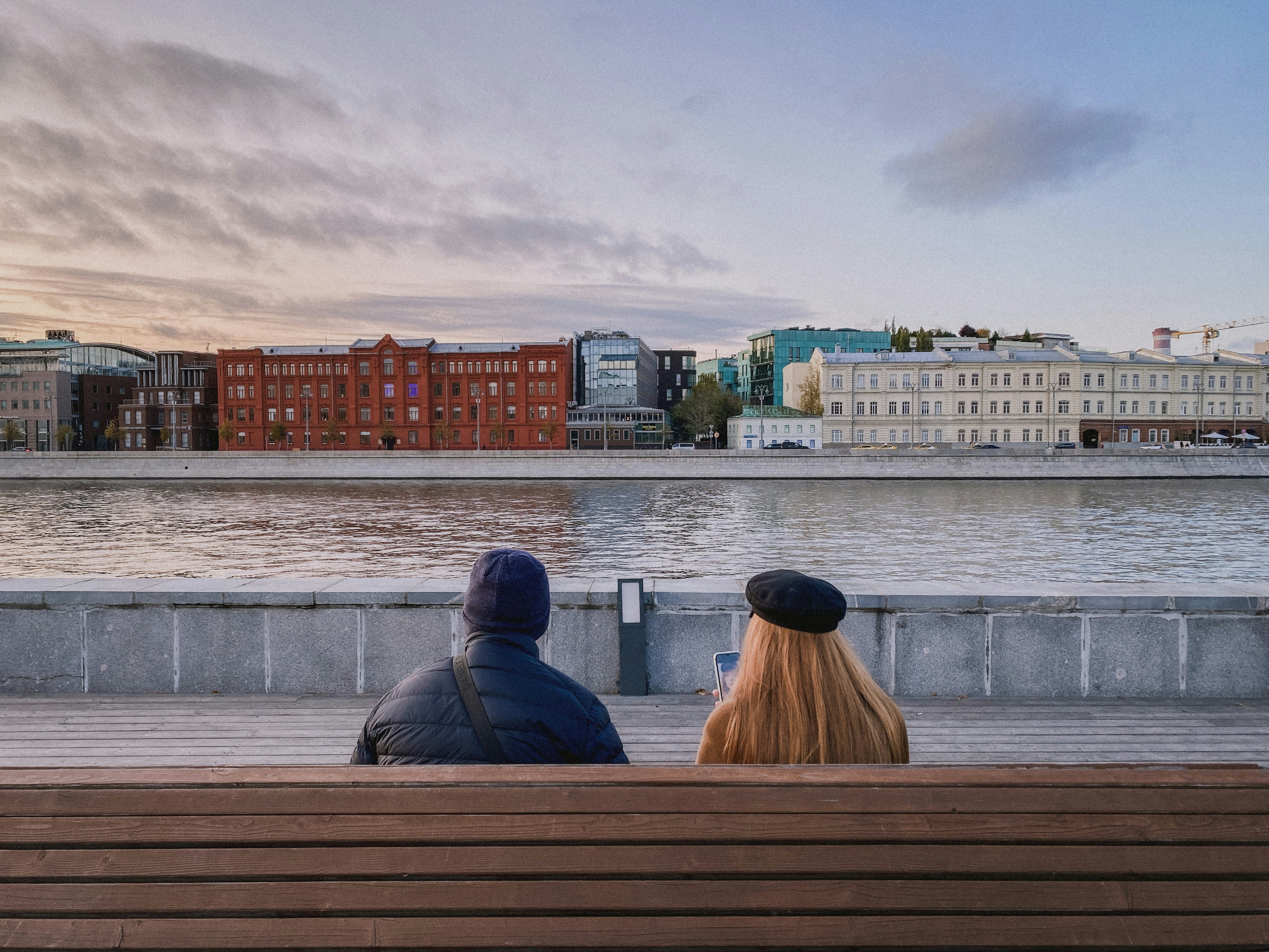 2 person sitting on brown wooden bench during daytime