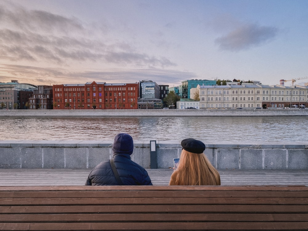 2 person sitting on brown wooden bench during daytime