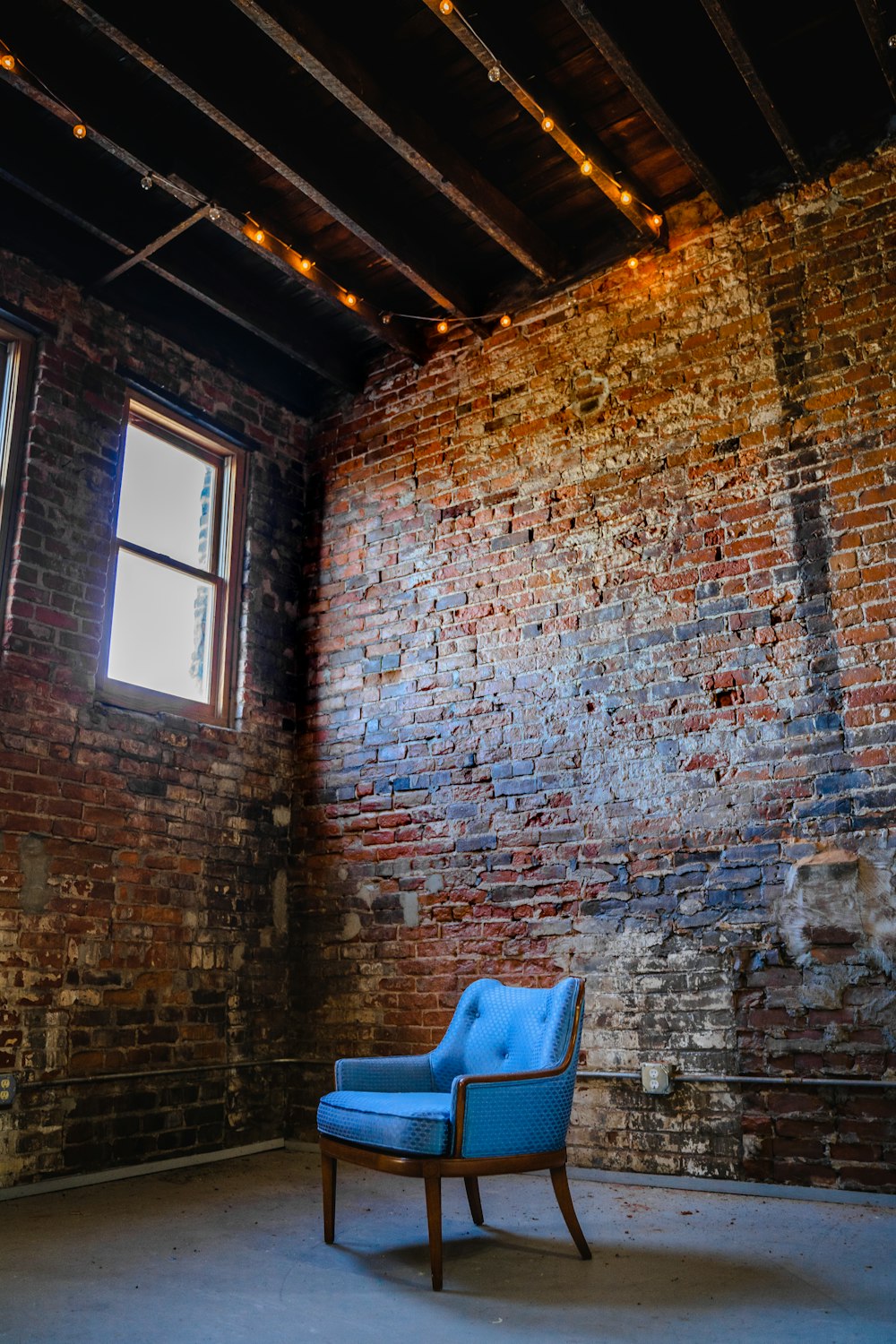 blue plastic chair beside brown brick wall