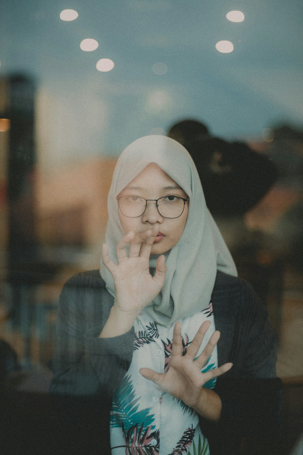 woman in white hijab covering her face with blue and white floral hijab