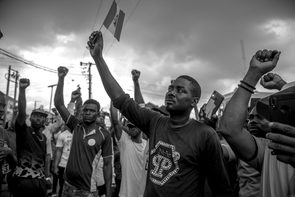 grayscale photo of man in crew neck t-shirt raising his hands