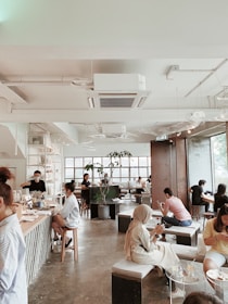 A bright, modern interior view of Ground Floor Cafe with customers enjoying coffee and working on laptops.