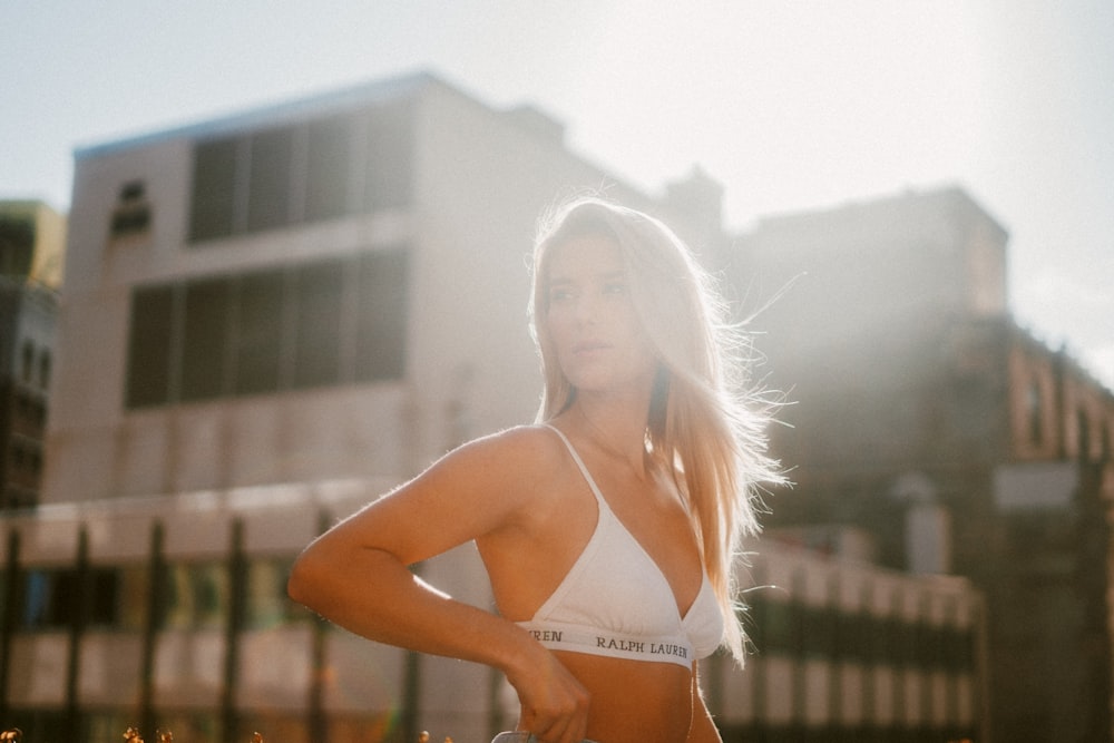 woman in white bikini top standing on brown wooden fence during daytime