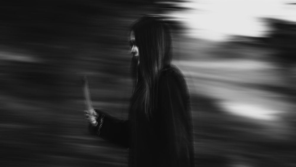 mulher no casaco preto em pé na estrada durante o dia