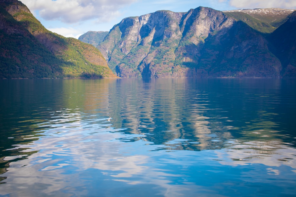 body of water near mountain during daytime