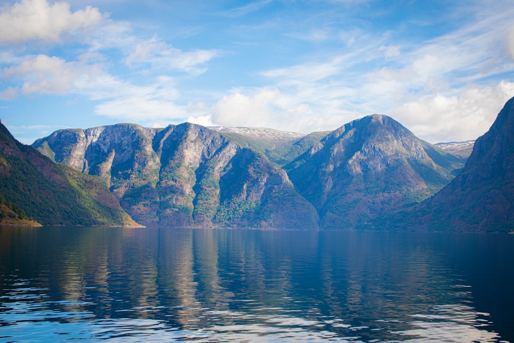 body of water near mountain during daytime