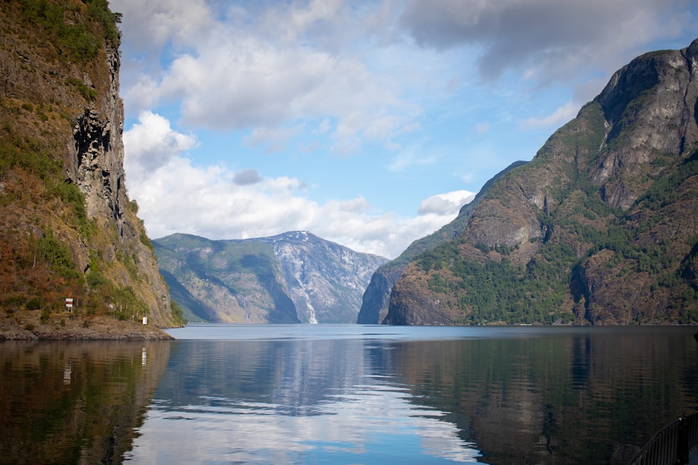 blue lake surrounded by green trees and mountains under blue sky and white clouds during daytime