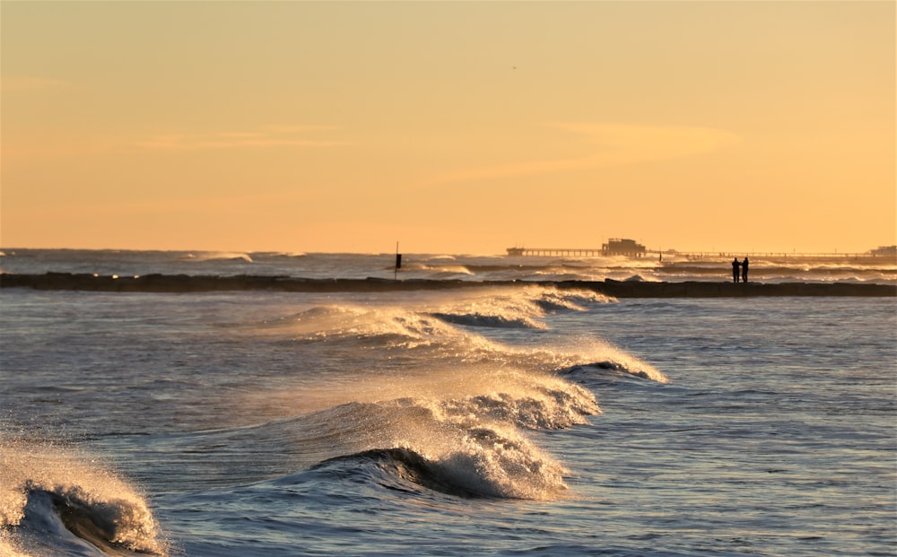 ocean waves crashing on shore during sunset