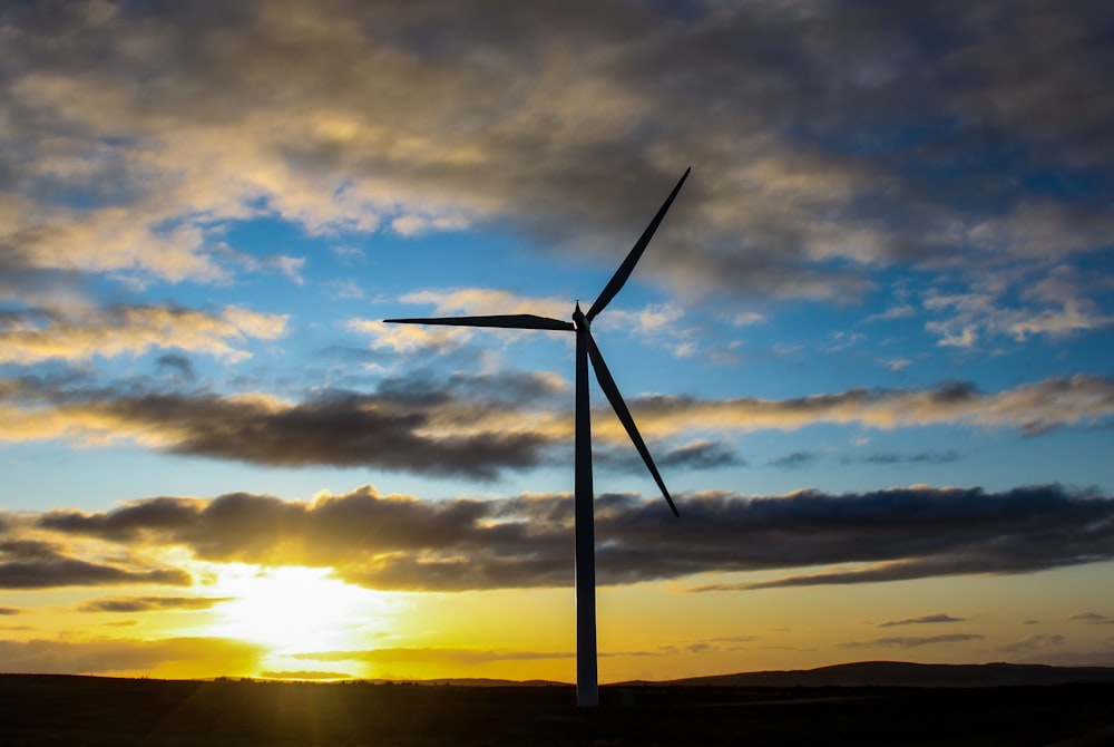 wind turbine under cloudy sky during sunset