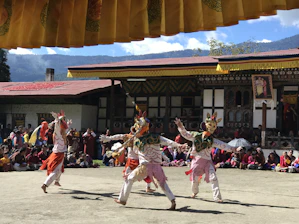 Traditional Croatian folk dancers in colorful costumes performing outdoors under a clear sky.