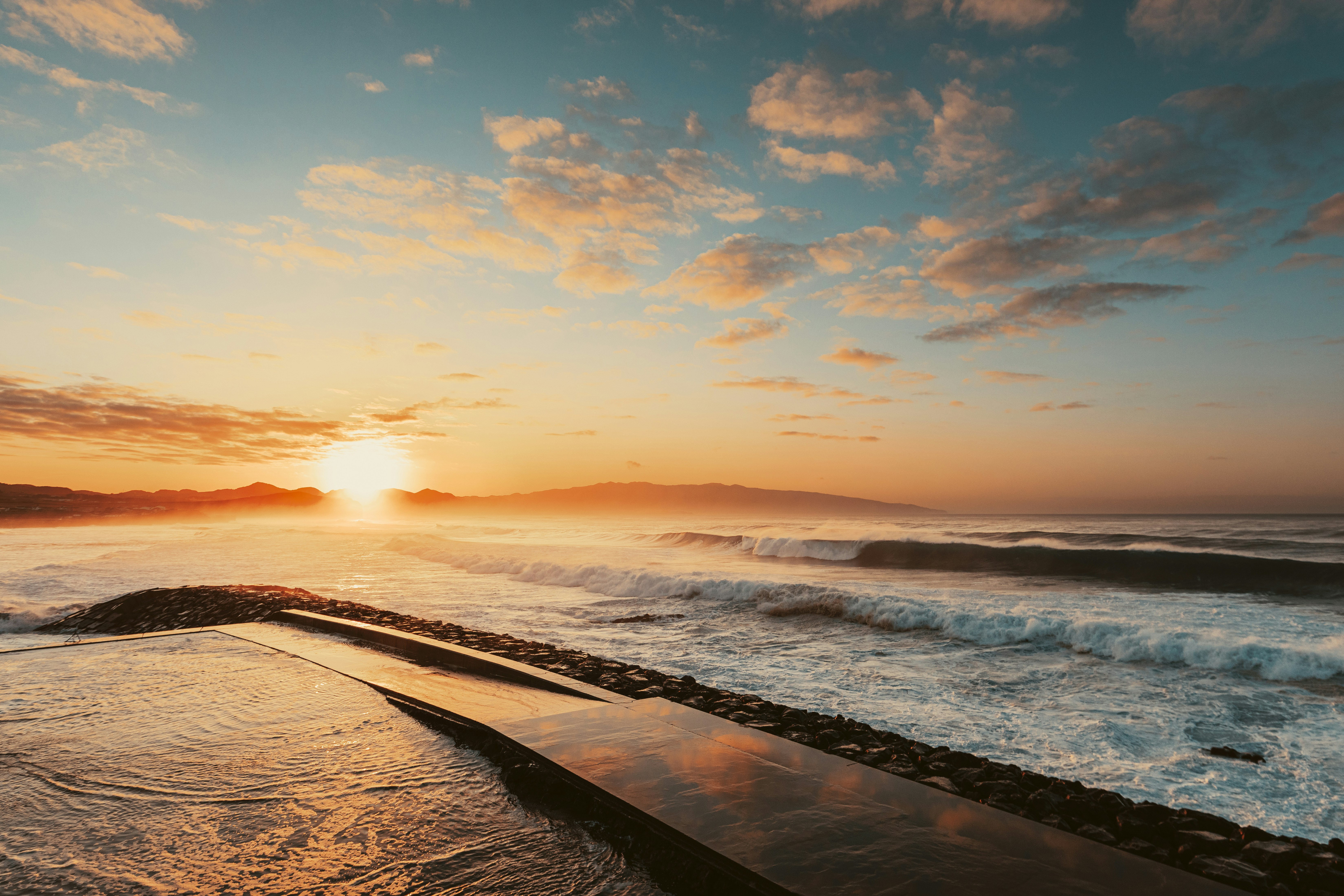 ocean waves crashing on shore during sunset