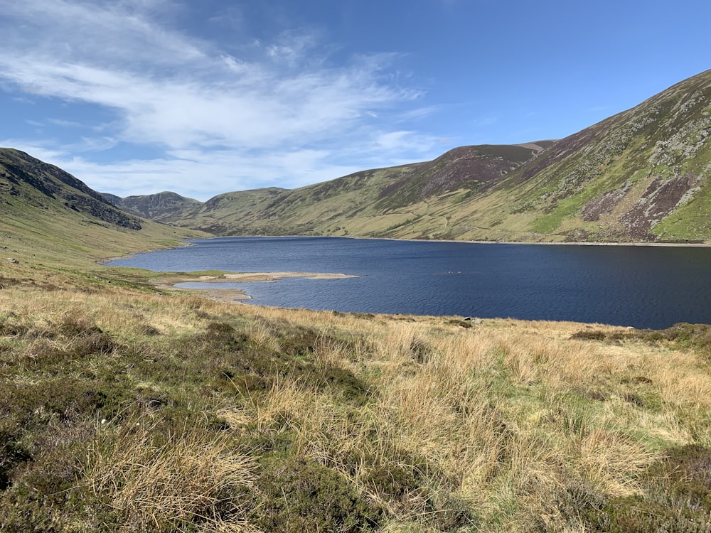 green mountains beside body of water under blue sky during daytime