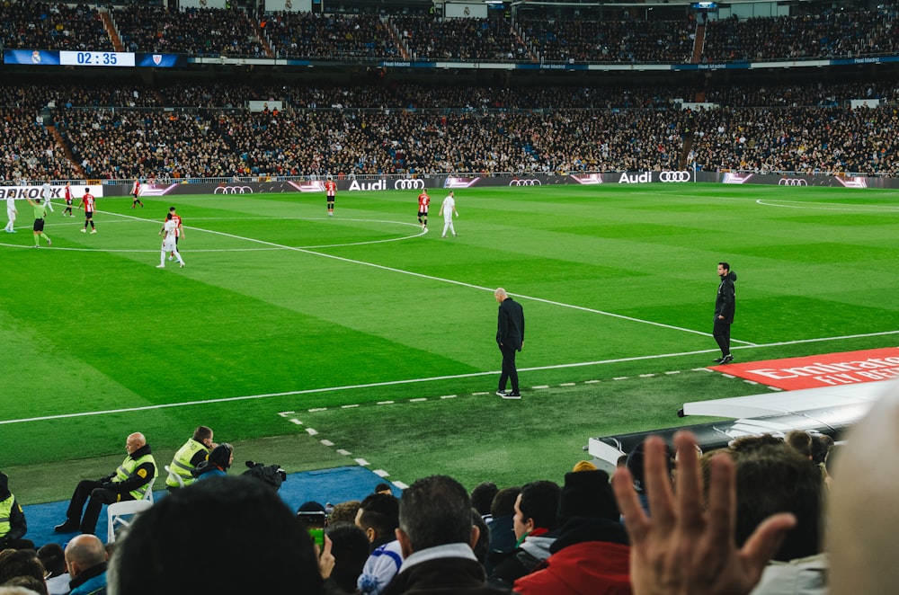 people watching soccer game during daytime