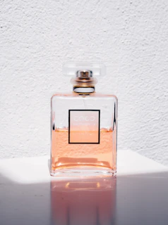 Minimalist serum bottle on a soft peach background with natural light highlighting its texture