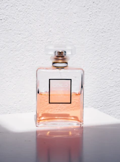 Close-up of a peach serum bottle glistening under soft light with subtle peach-colored background